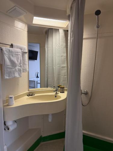a bathroom with a sink and a mirror at Mot Hotel in Claye-Souilly