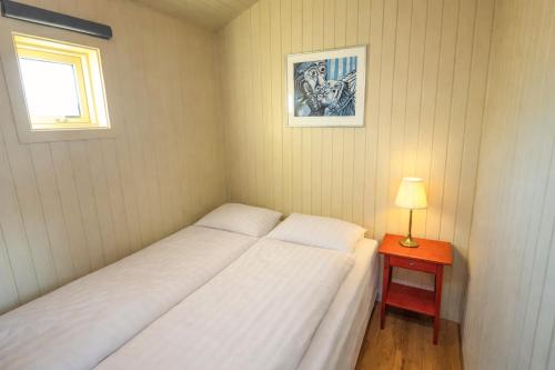 a bedroom with two beds and a table with a lamp at Fossatún Sunset Cottage in Fossatún