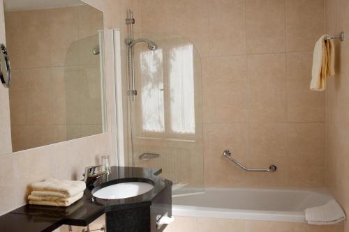 a bathroom with a sink and a tub and a shower at Hotel Landgut Burg in Weinstadt