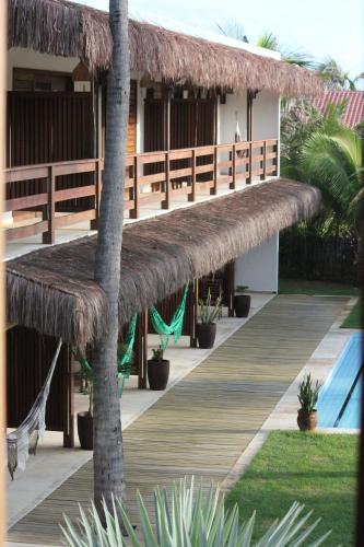 a resort with a deck and a thatch roof at Pousada Maresia in Guajiru