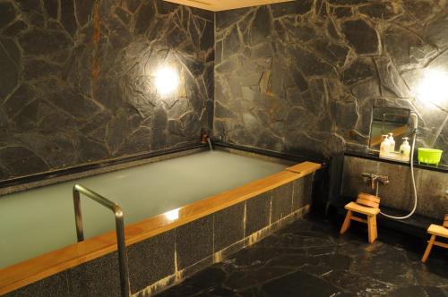 a bath tub in a room with a stone wall at Hotel Terrace Yokohama in Yokohama