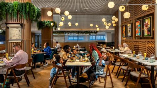 a group of people sitting at tables in a restaurant at Hilton London Metropole in London