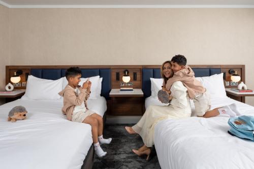 a family sitting on beds in a hotel room at Hilton London Metropole in London