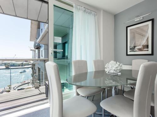 a dining room with a glass table and white chairs at Jibe Ho - Beautiful Spacious Apartment with Harbour Views in Poole