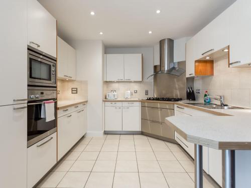 a large kitchen with white cabinets and white appliances at Jibe Ho - Beautiful Spacious Apartment with Harbour Views in Poole