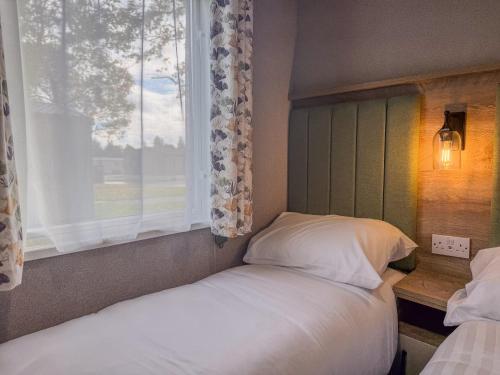 a bedroom with two beds and a window at Oakmont Lodge in Allerthorpe