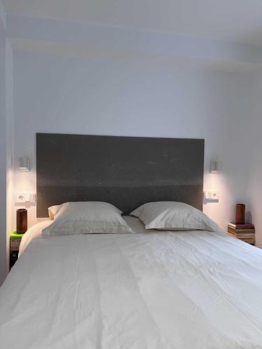 a large white bed with a black headboard and two pillows at Centro Histórico - Beneficencia Flat in Valencia