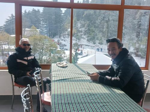 two men are sitting at a table in a restaurant at Amazing view Home Stay in McLeod Ganj