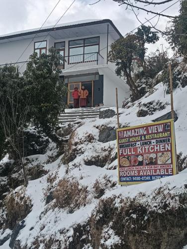 two people standing in front of a house in the snow at Amazing view Home Stay in McLeod Ganj