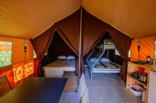 a tent with a table and a bed in it at Camping Onlycamp la Rochette in Guillestre