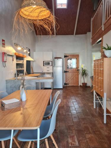 a kitchen with a wooden table and blue chairs at Alba Odeceixe - casa blanca in Odeceixe
