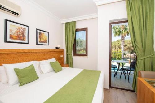 a bedroom with a bed and a balcony with a table at Fethiye Park Hotel in Fethiye