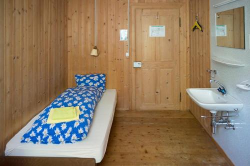 a room with a bed and a sink and a door at Berggasthaus Voralp in Grabs
