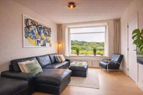 a living room with a couch and chairs and a window at Beachhouse Wijk aan Zee 6 guests near beach free parking in Wijk aan Zee