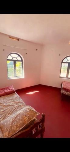 an empty room with a bed and two windows at Westernmagic in Idukki