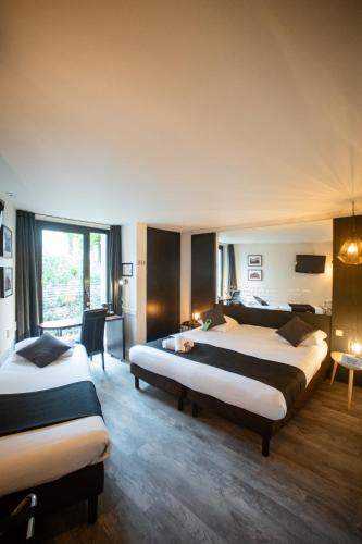 a hotel room with two beds and a desk at Logis Hôtel Des Acacias Lille Neuville en Ferrain, Restaurant l'Acacias Gourmand in Neuville-en-Ferrain
