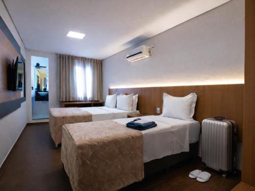 ein Hotelzimmer mit zwei Betten und einem Koffer in der Unterkunft Hotel Ouro Mel in Santa Bárbara