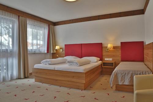 a bedroom with two beds with red headboards at Hotel Moawirt in Wagrain