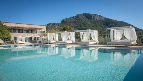 a pool with white chairs and a mountain in the background at Finca Binibona Parc Natural in Binibona