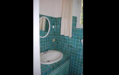 a blue tiled bathroom with a sink and a mirror at Gîte dans les vignes la calade in Grimaud