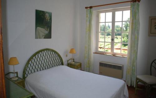 a bedroom with a white bed and a window at Gîte dans les vignes la calade in Grimaud