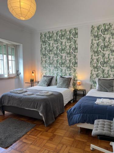 a bedroom with two beds and a wall with wallpaper at Alvalade II Airport Guest House in Lisbon