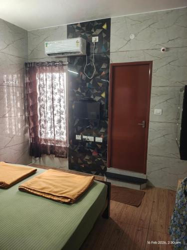 a room with two beds and a wall with a window at Sri Madapallii in Tiruchirappalli