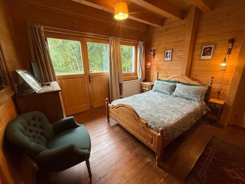 a bedroom with a bed and a chair in a cabin at Alpine Lodge in Pentney