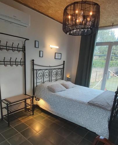 a bedroom with a bed and a chandelier at Le tiny de Laly - climatisation -wifi - jardin - airport navette in Pont-de-Loup