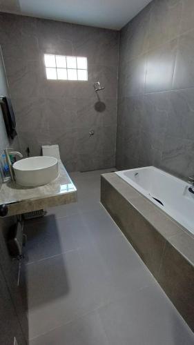 a bathroom with a tub and a sink and a bath tub at Villa Kitima homestay in Ban Chat