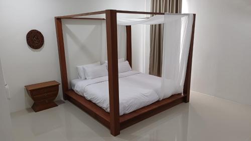 a wooden canopy bed with white sheets and pillows at Villa Kitima homestay in Ban Chat