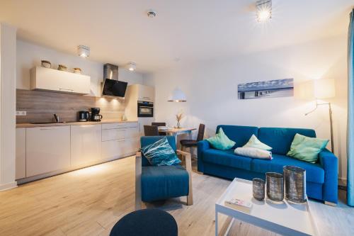 a living room with a blue couch and a kitchen at Am Park 14 in Prerow