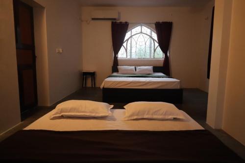 two beds in a room with a window at Hidden Pearl Beach Villa in Pondicherry
