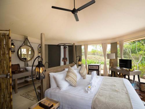 une chambre avec un lit avec un ventilateur de plafond dans l'établissement Menjangan Dynasty Resort, à Banyuwedang