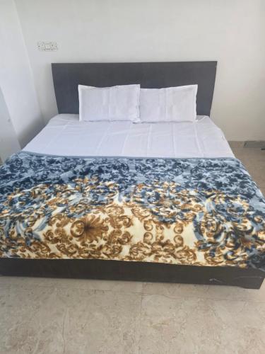 a bed with a blue and gold blanket on it at Bipl House Stay in Greater Noida