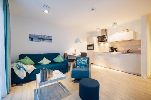 a living room with a blue couch and a kitchen at Am Park 13 in Prerow
