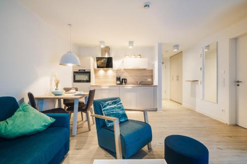 a living room and kitchen with a blue couch and a table at Am Park 13 in Prerow