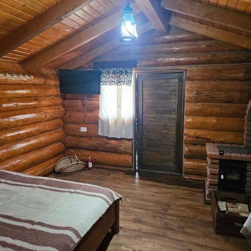 a bedroom of a log cabin with a bed and a window at Căbănuțe lemn cu ciubăr in Varvata