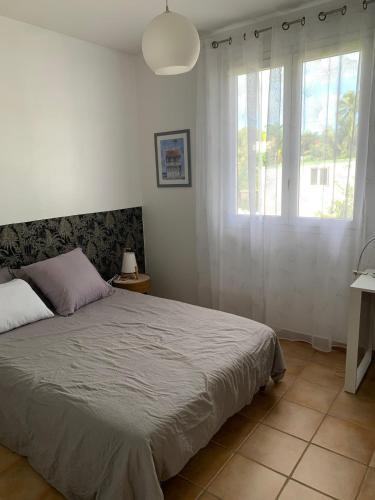 a bedroom with a bed and two windows at Chic, bright and quiet in Baie-Mahault