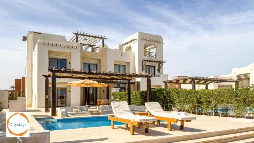 a villa with a swimming pool in front of a house at Heated Pool 4BR Villa, Lagoon Front, Ancient Sands - OllyStays in El Gouna