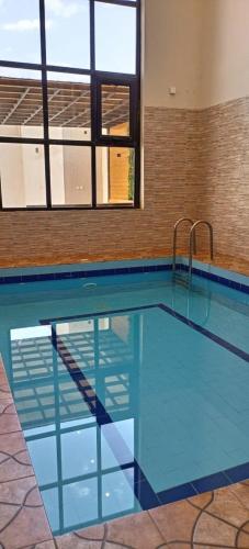 a large swimming pool with blue water in a building at شاليهات بيات فيلا نورسين in Abha