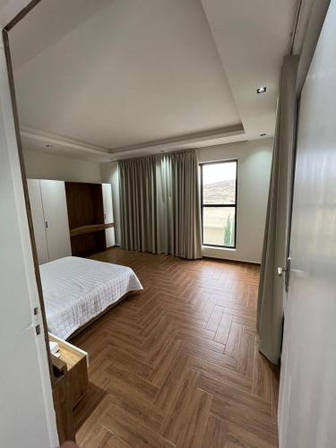 a bedroom with a bed and a large window at شاليهات بيات فيلا نورسين in Abha