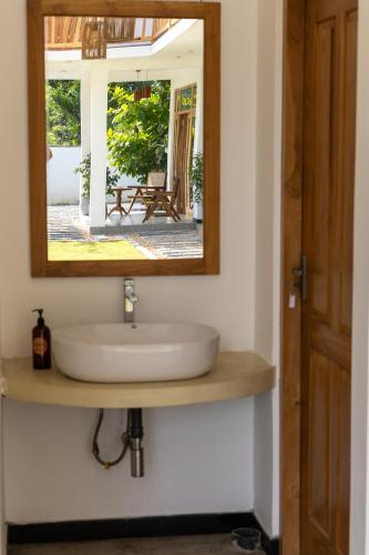 a bathroom with a sink and a mirror at Beach House by Unrushed in Welhengoda