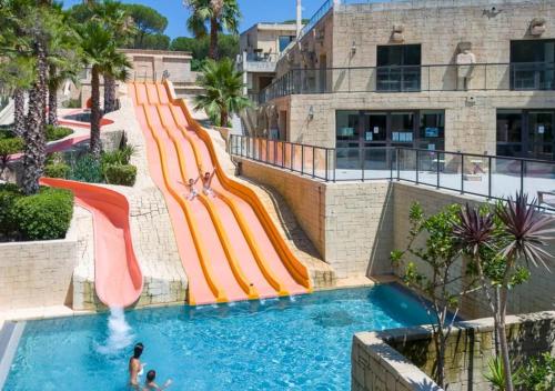 a water slide in a pool at a resort at Camping Les Cigales - Aquatique Vacances in Le Muy