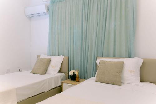 two beds in a room with blue curtains at Kymo Fig Tree Bay House in Protaras