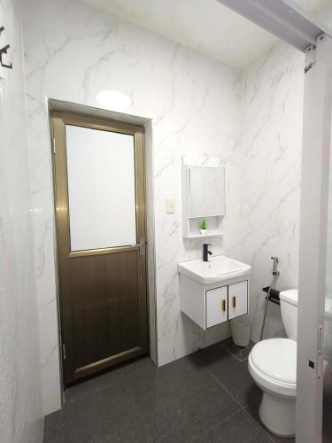 a bathroom with a toilet and a sink and a door at Casipe Transient House in Tanay