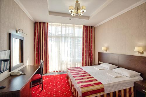 um quarto de hotel com uma cama e uma grande janela em Sonata Hotel em Sochi
