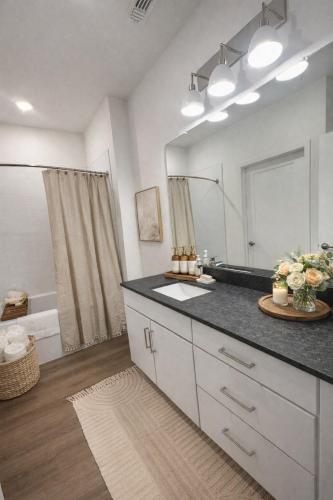 a bathroom with a sink and a large mirror at Boho Boutique Retreat - Pool - Gym - Private Patio in Tampa