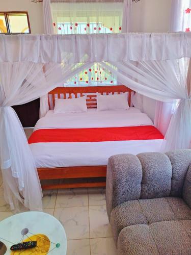 a bedroom with a bed with a canopy and a couch at Adventure studio apartment in Mtwapa