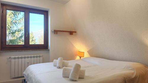 a bedroom with a white bed with towels on it at Hostdomus - La Tana della Volpe in Sauze d'Oulx